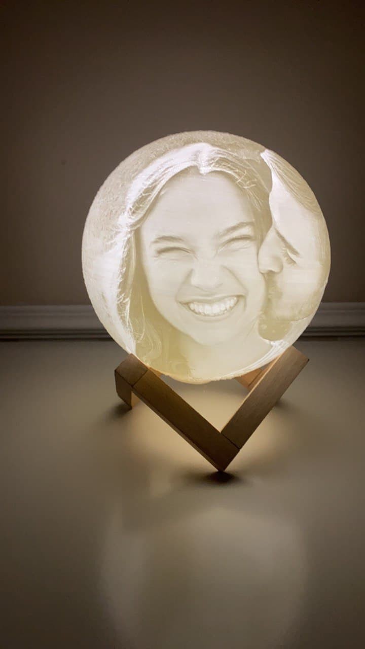 Lámpara Luna 3D personalizada con foto, montada en un soporte de madera e iluminada en primer plano.